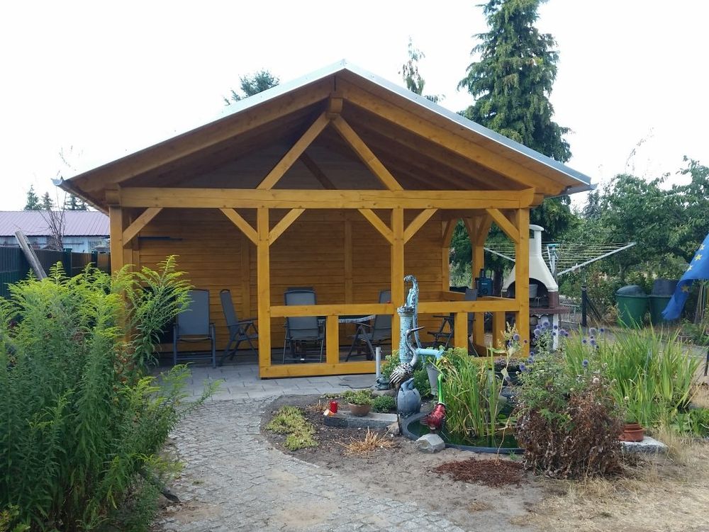 Gemütliches Gartenhaus mit Holzterrasse und Gartenpflanzen.