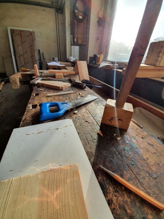 Eine Werkbank mit verschiedenen Holzwerkzeugen und Materialien in einer Werkstatt