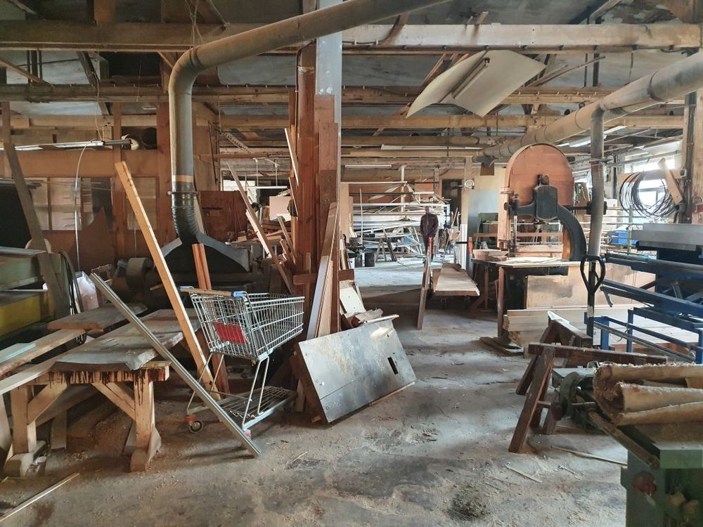 Innenansicht einer Werkstatt mit Holz und Maschinen.