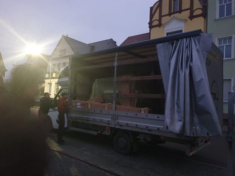 Ein Umzugs-Lkw, der Möbel entlädt, während es dämmert.