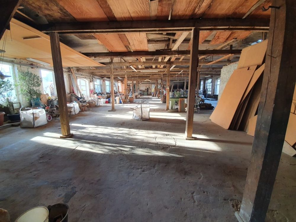 Innenansicht eines großen Lagerraums mit Holzstützen und Tageslicht.