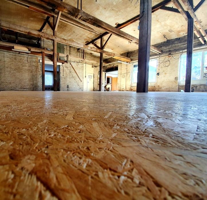 Blick auf den Boden einer renovierten Werkstatt mit Holzstützen.