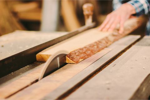 Ein Handwerker schneidet ein Holzstück mit einer Tischsäge.