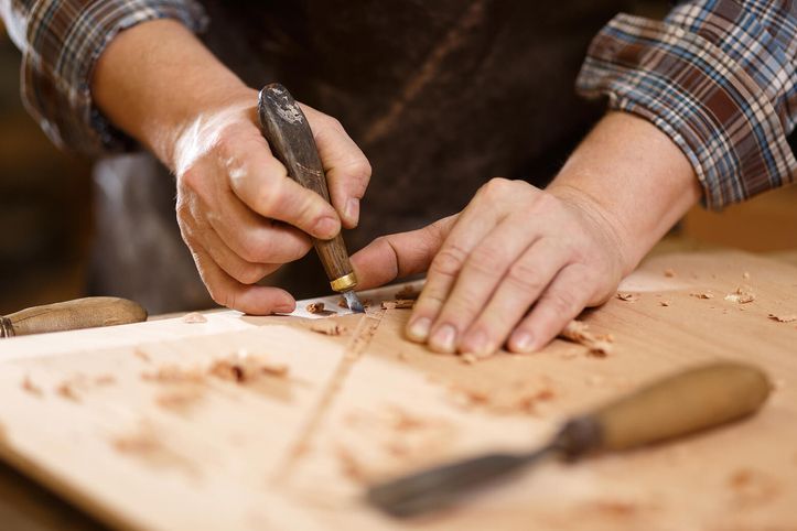 Handwerker schnitzt Holz mit einem Schnitzmesser.